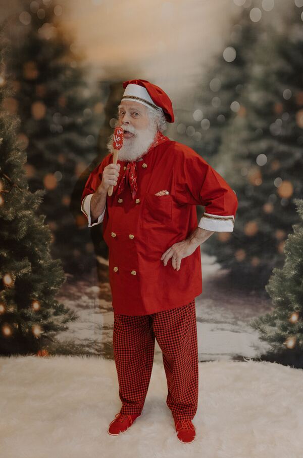 Santa Ray in his red jacket among snowy Christmas trees