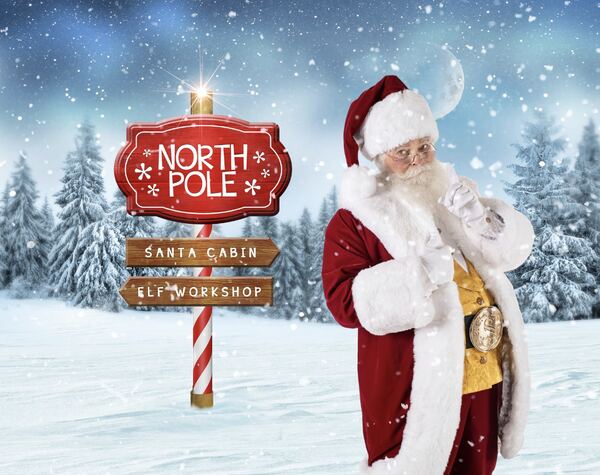 Santa Ray beside a North Pole signpost in the snow
