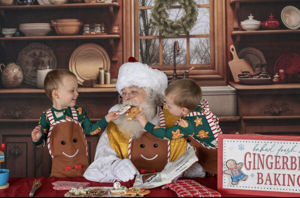 Two children with gingerbread treats and Santa Ray in a baking kitchen
