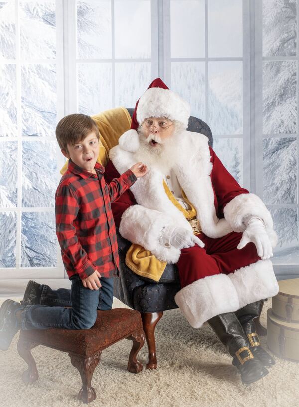 A boy and his dog visiting Santa Ray by a frosted window
