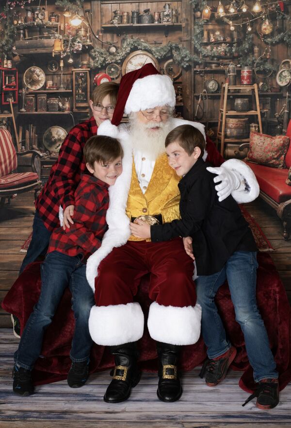 Two boys sitting with Santa Ray in his workshop