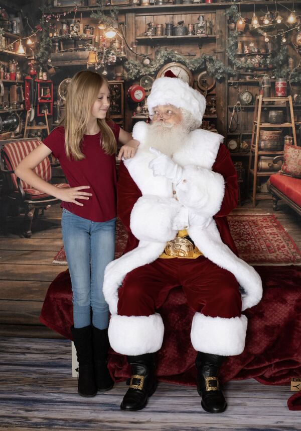 A mother posing with Santa Ray in his workshop