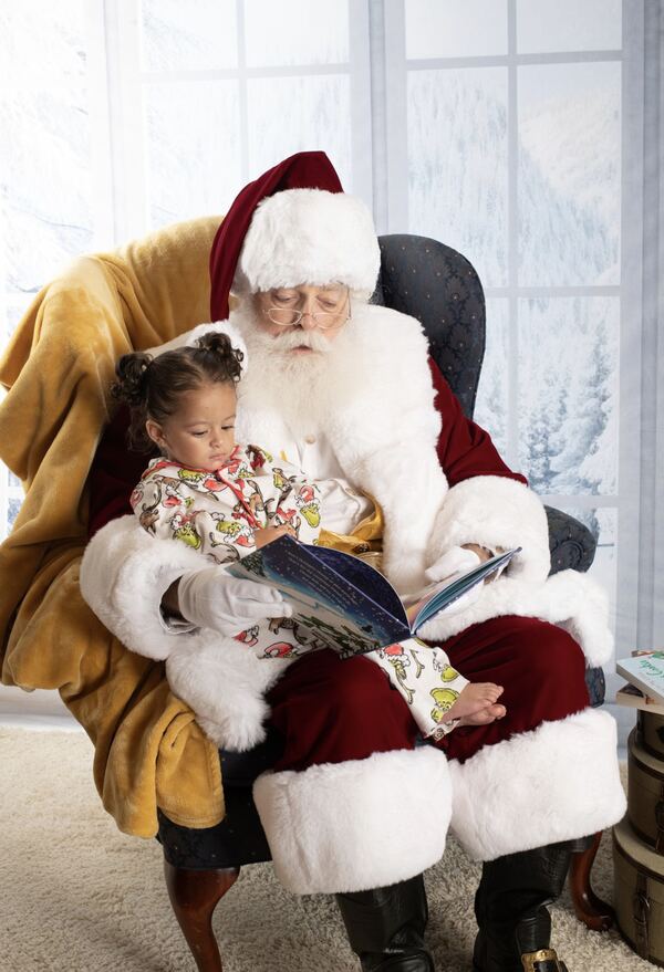 Santa Ray reading a book with a little girl on his lap