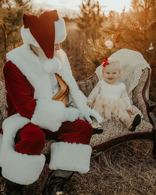 Santa Ray sitting beside a baby on an antique chair outdoors