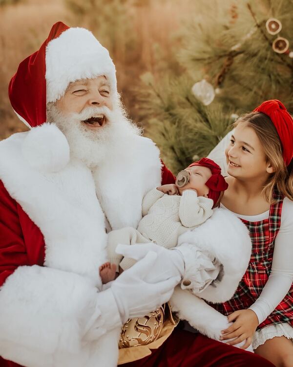 Santa Ray laughing with a mother and her baby