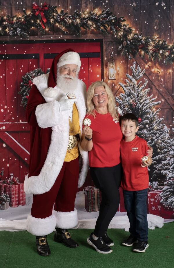 Santa Ray with a mother and son in front of a red barn door
