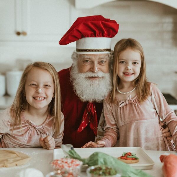 Two sisters smiling with Santa Ray at the table