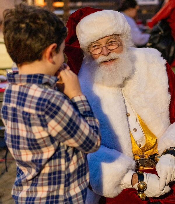 A boy in a plaid shirt talking with Santa Ray