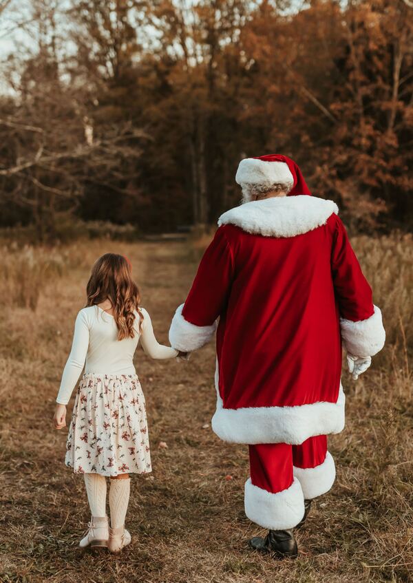 Santa Ray walking hand in hand with a girl through a golden field