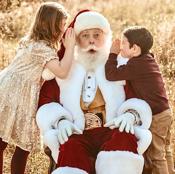 A girl and a boy sharing secrets with Santa Ray at golden hour
