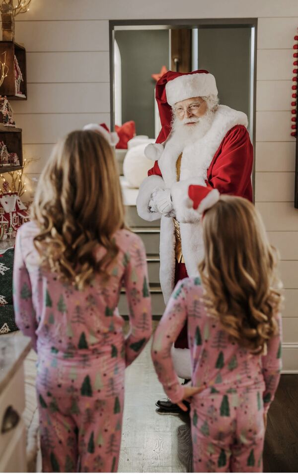 Two girls in pajamas meeting Santa Ray in their kitchen