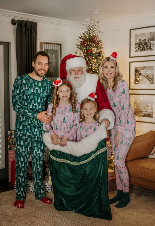 A family in matching pajamas with Santa Ray