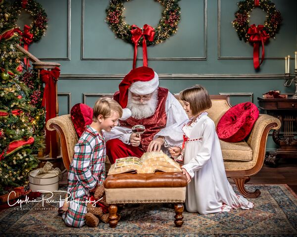 Santa Ray reading a big storybook to two children