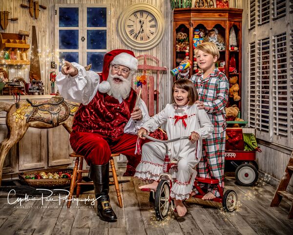 Santa Ray with children and a red tricycle in his workshop