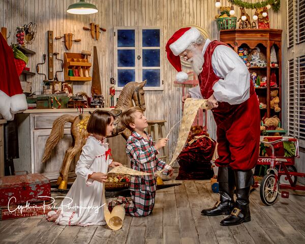 Santa Ray handing a present to a child in his workshop