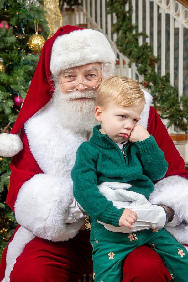 A toddler in green sitting on Santa Ray’s lap